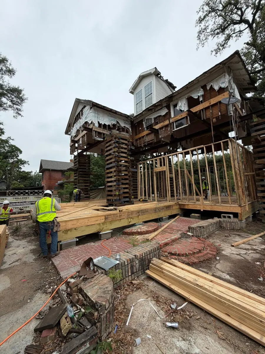Crew in safety vests framing beneath a raised home